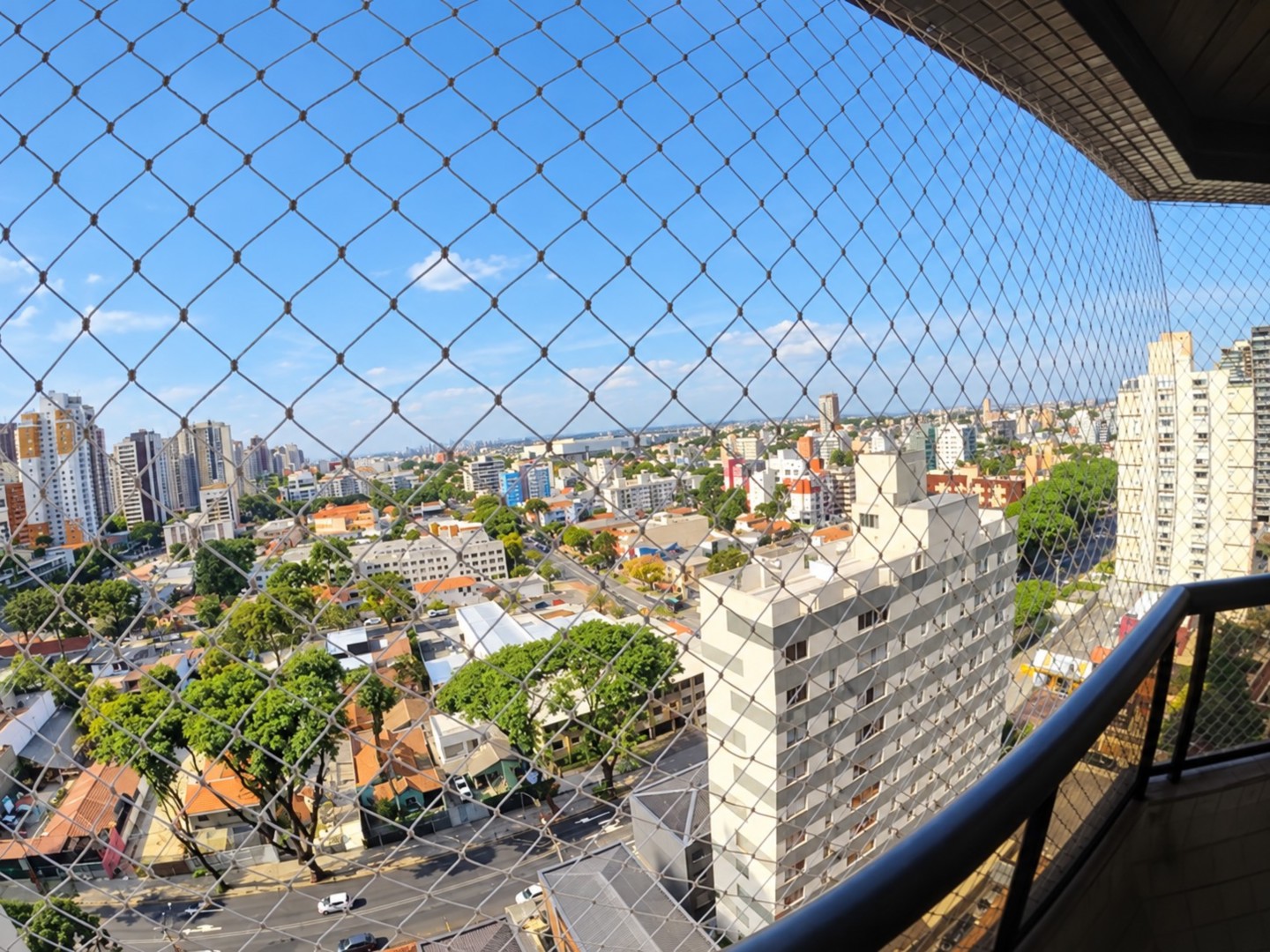 Vista urbana ensolarada pela varanda.png