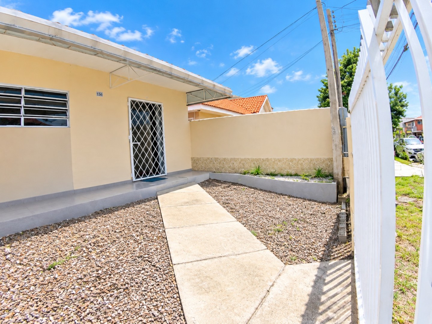 Pátio ensolarado com casa número 156.png