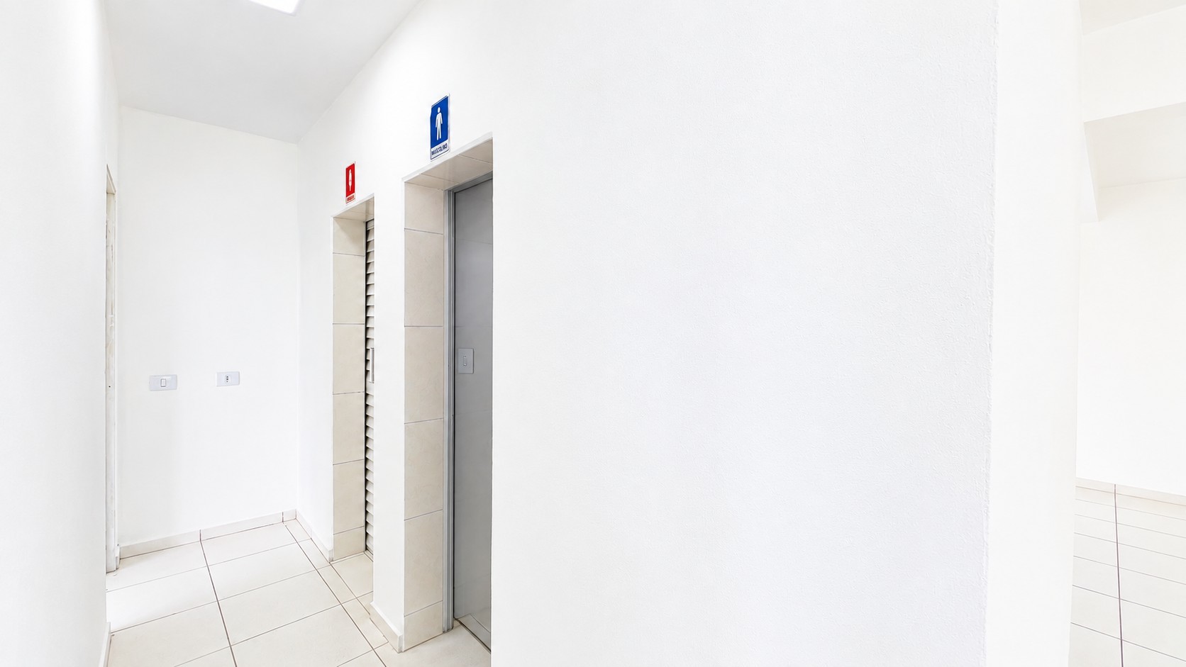 Corredor Branco com Elevadores e Sinalização.png